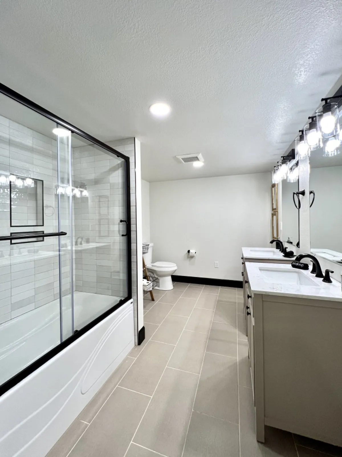 A sophisticated bathroom with a glass shower enclosure, dual sinks with modern faucets, and stylish lighting fixtures. The space feels airy and bright, with morning light streaming through the glass, adding a touch of spa-like luxury.
