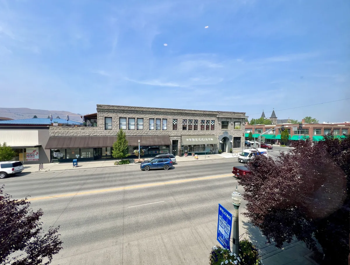 A bustling downtown street scene featuring a historic building facade with visible signage and lively street activity. The image conveys the energy of local events, art fairs, and the everyday vibrancy of Main Street.