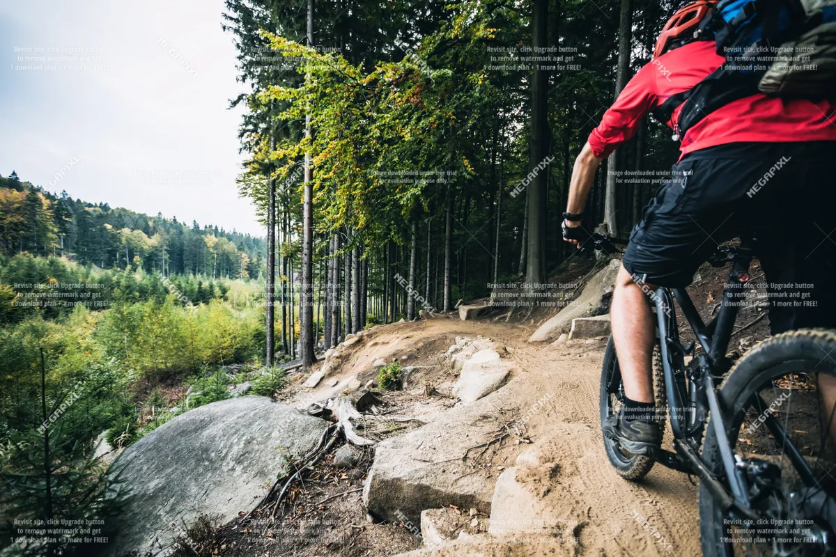 A mountain biker navigates a rugged, rocky trail surrounded by trees, reflecting the exhilarating opportunities for outdoor recreation in the area.