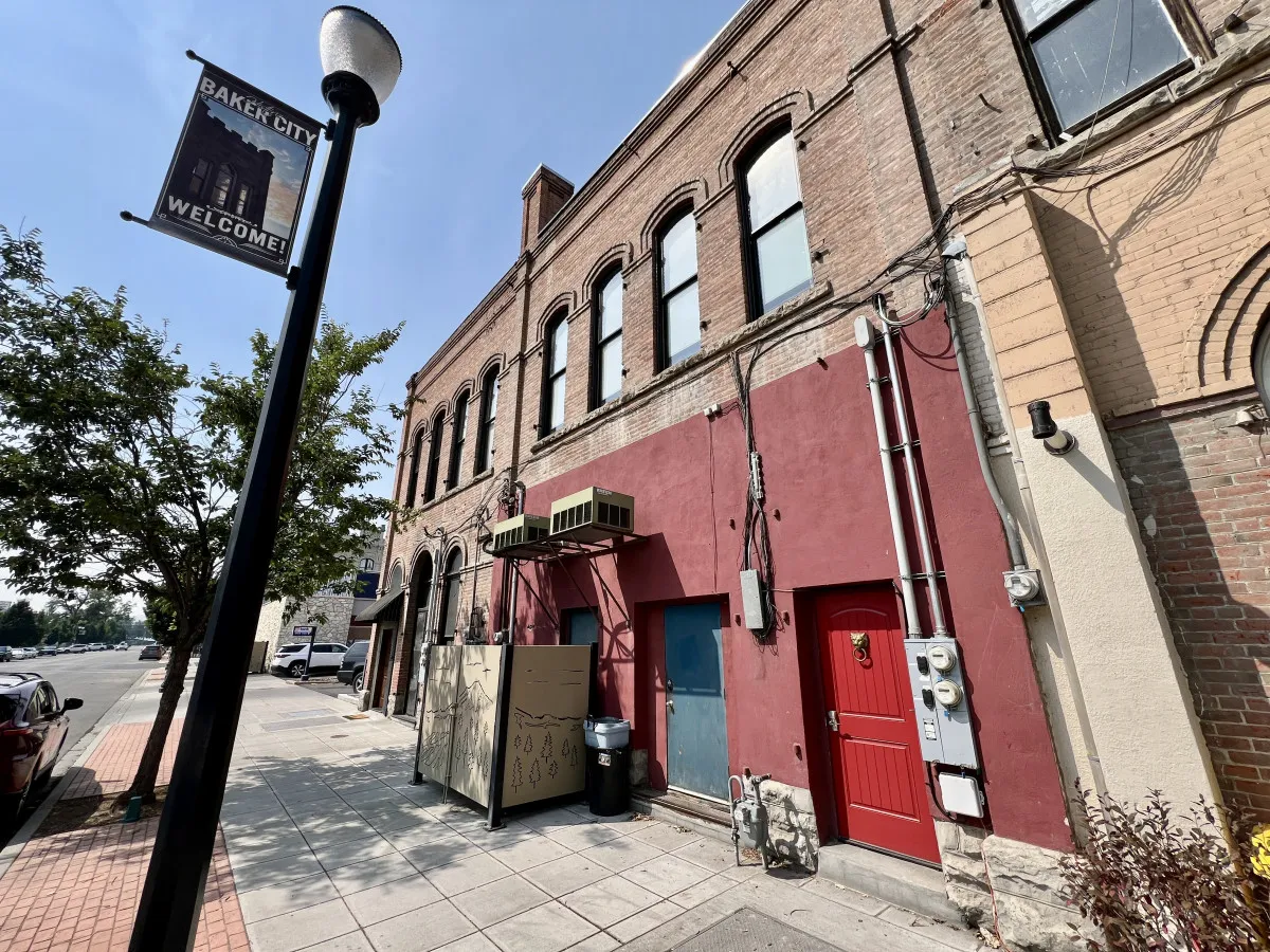 A welcoming brick facade with a striking red door and an inviting welcome sign, set against the backdrop of a walkable street. The scene suggests the charm of local shops and the ease of exploring the neighborhood on foot.